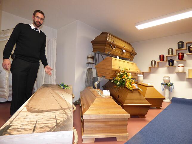 Heinz Vogt vom Bestattungunternehmen Vogt zeigt auf einen individuell angefertigten Sarg.