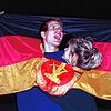 Ein jubelndes Paar hat sich am Tag der Deutschen Einheit 1990 am in einer DDR-Fahne dort Platz geschaffen, wo früher das Emblem Hammer ...