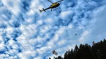 Ein Lastenhelikopter fliegt ein Teil eines alten Strommasten aus. Er hatte in unwegsamen Gelände gestanden.