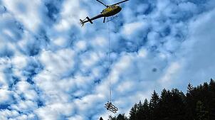Ein Lastenhelikopter fliegt ein Teil eines alten Strommasten aus. Er hatte in unwegsamen Gelände gestanden.