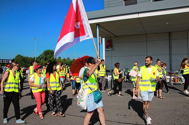 Mit Gewerkschaftsfahnen und Warnwesten ziehen Beschäftigte aus dem Einzelhandel vor den Haupteingang des Kauflands in Bad Dürrheim.
