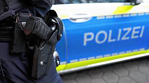 Ein Polizist steht vor einem Einsatzfahrzeug der Polizei. (Symbolbild)