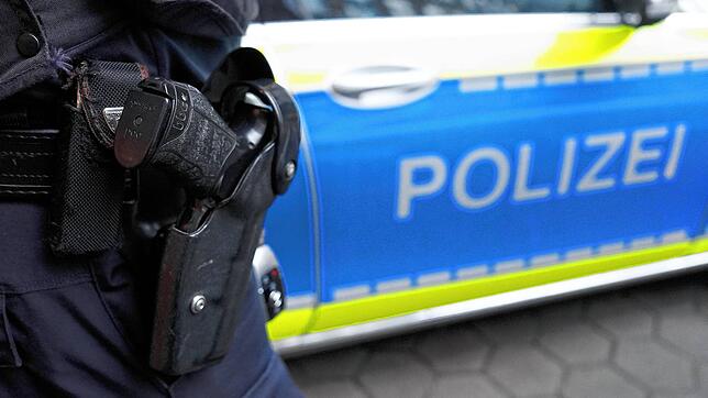 Ein Polizist steht vor einem Einsatzfahrzeug der Polizei. (Symbolbild)