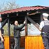 Bürgermeister Thorsten Scigliano (Mitte) begutachtet mit zwei Polizisten den Schaden an der Hütte.