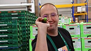 Der Dortmunder Maximilian Czerwinski hat in der Halle der Reichenauer Gemüse eG eine Snackgurke wie einen Dartpfeil in der Hand. Seinem ...
