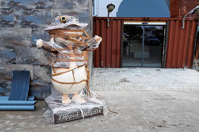 Maskottchen Flippi steht noch eingepackt vor dem Eingang.