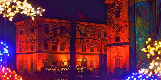 Das Barockschloss wird in wechselnd bunte Farben getaucht.