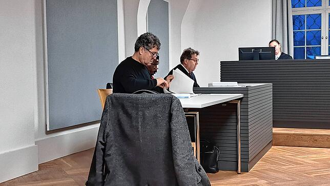 Der Angeklagte sitzt neben seinem Verteidiger Hubert Mangold (hinten) und seinem Dolmetscher.
