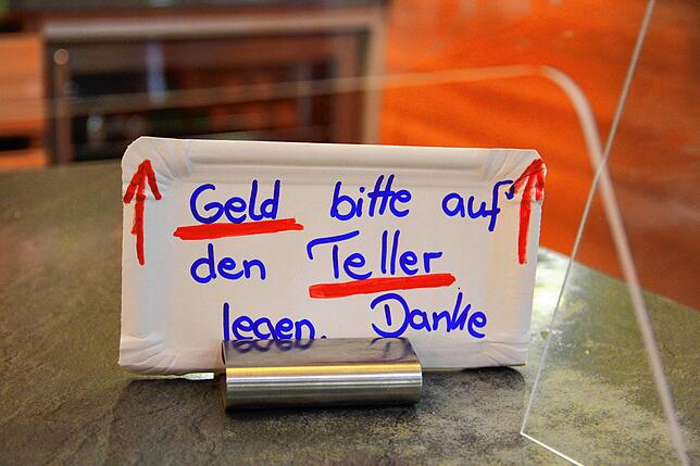Spuckschutz und provisorische Geldübergabe in der Filiale. Die meisten halten sich dran, einige poltern auch.
