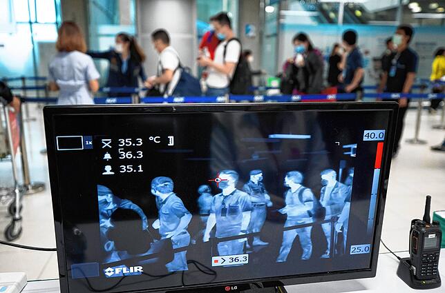 Touristen wird bei deren Ankunft an einem Flughafen mit einem Scanner die Körpertemperatur gemessen.