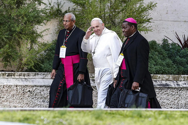 Papst Franziskus (Mitte) geht mit zwei Bischöfen durch die Vatikanstadt.