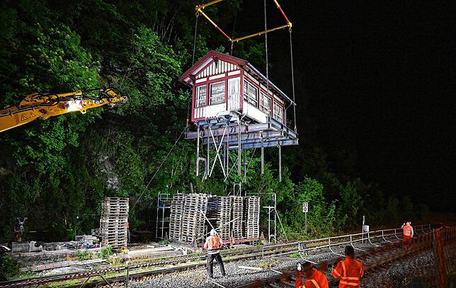 Ein ausrangiertes Stellwerksgebäude wird in Calw an einer Bahnstrecke am Stück von einem Kran über die Gleise gehoben.