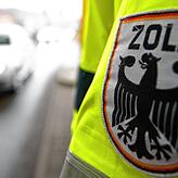 Ein Zollbeamter steht in Gottmadingen an der deutsch-schweizerischen Grenze und kontrolliert Fahrzeuge.