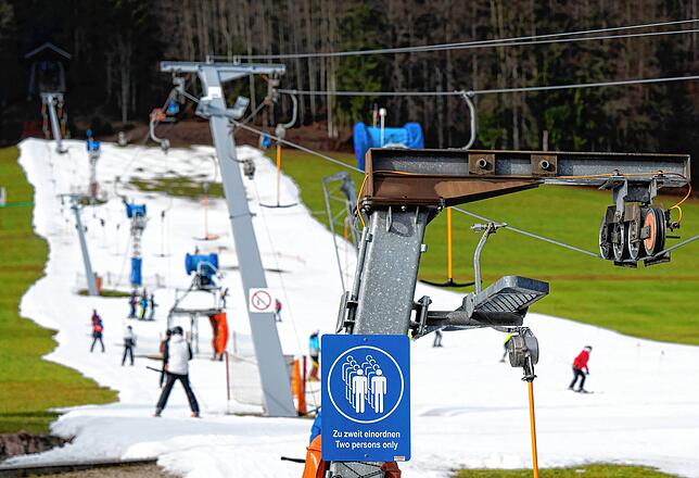 Mitte Januar in Ruhpolding: Skifahrer fahren bei schönem Wetter auf einer Skipiste – drumherum Wiese.