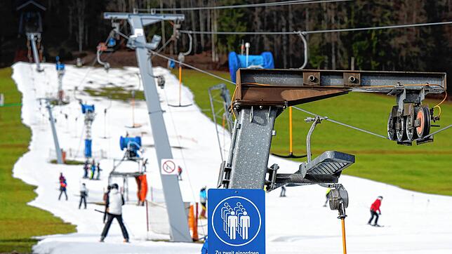 Mitte Januar in Ruhpolding: Skifahrer fahren bei schönem Wetter auf einer Skipiste &ndash; drumherum Wiese.