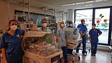 In den Wärmebettchen liegen die Drillinge, davor stehen die Kinderärzte und Kinderkrankenschwestern, die die drei Frühgeborenen ...