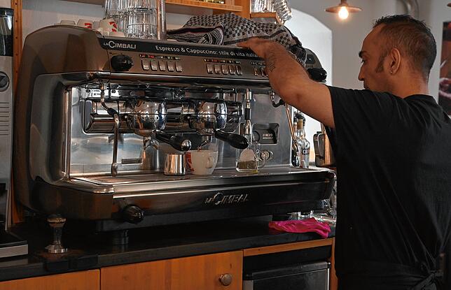 Mitarbeiter Cristian Corrado bereitet Getränke hinter der Bar zu. Dazu gehört in italienischer Manier auch die Siebträgermaschine für ...