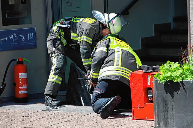 Feuerwehrleute untersuchen den Lüftungsschacht vor dem Rathaus.