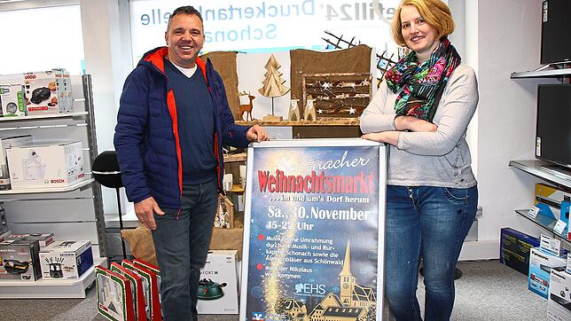 Einzelhändler-Vorsitzender Michael Dold und Kassiererin Melanie Rombach präsentieren das Plakat für den Schonacher Weihnachtsmarkt am ...