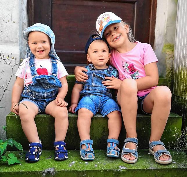 Die Zwillinge Elin und Anian mit Schwester Maelle in Mengen auf der Treppe der Martinskirche vor Omas und Opas Haus.