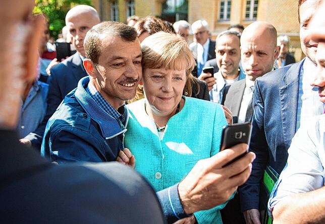 Angela Merkel macht im September 2015 mit einem Asylbewerber ein Selfie.