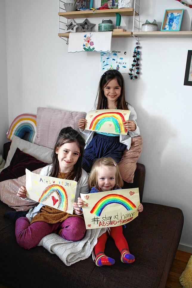 Liselotta (8 Jahre), Mieke (6 Jahre) und Tilda (2 Jahre) haben Regenbögen gemalt, die sie ins Fenster hängen.
