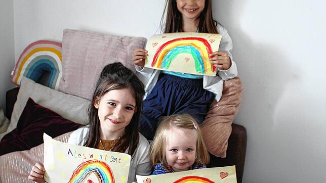 Liselotta (8 Jahre), Mieke (6 Jahre) und Tilda (2 Jahre) haben Regenbögen gemalt, die sie ins Fenster hängen.
