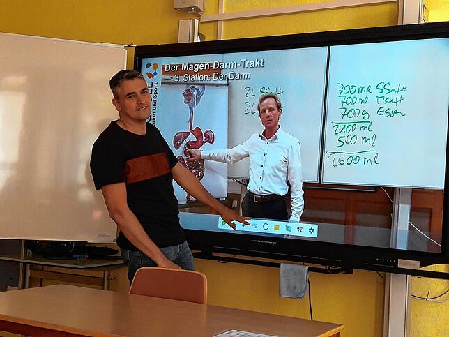 Verwaltungsleiter Martin Propp zeigt das interaktive Whiteboard, auf dem ein Online-Kurs der VHS zu sehen ist zum Thema Magen-Darm, der ...