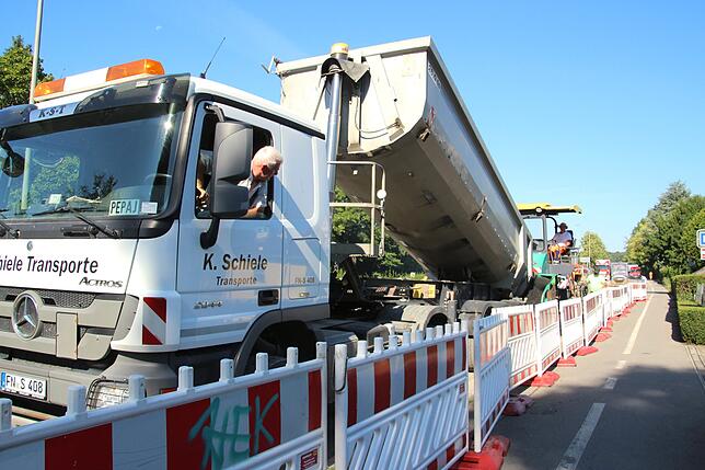 Der LKW kippt das heiße Gemisch aus. Sofort danach wird es mit dem Asphaltfertiger verarbeitet.