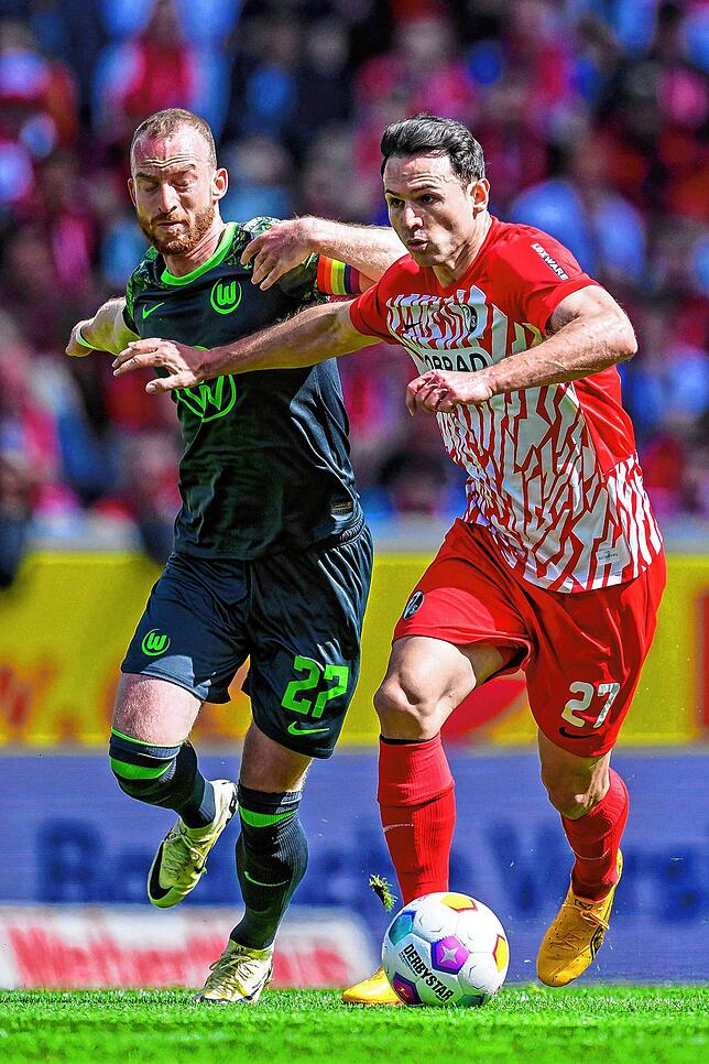 Wolfsburgs Maximilian Arnold (l) in Aktion gegen Freiburgs Nicolas Höfler (r).
