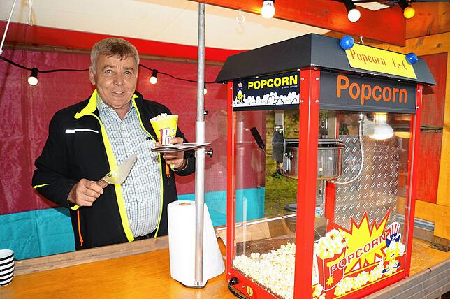 Ehrenzunftmeister Rolf Weißenrieder bietet warme Süßigkeiten aus der Popcornmaschine.