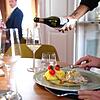 In einem Restaurant schenkt ein Kellner einem Gast Wein ein. Gastronomen befürchten, dass durch die Mindestlohnerhöhung die Preise für ...