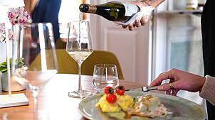 In einem Restaurant schenkt ein Kellner einem Gast Wein ein. Gastronomen befürchten, dass durch die Mindestlohnerhöhung die Preise für ...