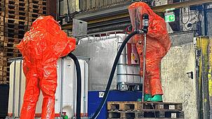 Mit entsprechender Schutzkleidung pumpt die Feuerwehr das Wasserstoffperoxid in einen unbeschädigten Behälter um.