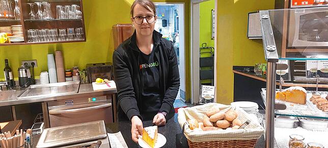 Johanna Schmid reicht einen Orangen-Polenta-Kuchen über die Theke. Das Gebäck ist seit vielen Jahren sehr beliebt im Suppengrün.