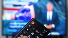 Ein Mann hält eine Fernbedienung vor einen Fernseher, auf dem die &bdquo;Tagesschau&ldquo; der ARD läuft. Gerade haben die ...