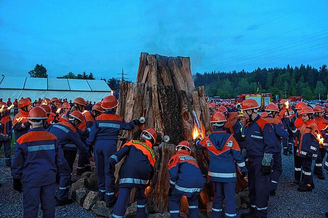 Hunderte Mädchen und Buben der Jugendfeuerwehr in Uniform und mit Fackeln beim Zeltlager 2023 in Schwenningen.