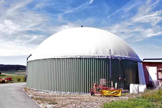 In diesem großen Behälter zersetzen Bakterien organisches Material und produzieren Biogas, das dann in einem Generator im Nebengebäude ...