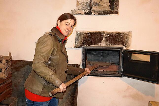 Christina Hopstock zeigt, wie der behutsam restaurierte Ofen genutzt wird.