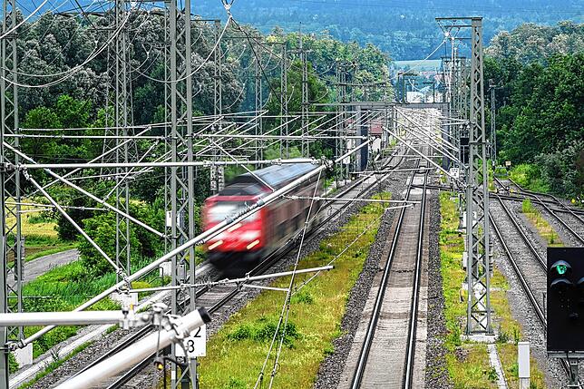 Eine Diesellok fährt 2021 auf der Südbahnstrecke von Ulm nach Friedrichshafen unter den neu installierten Oberleitungen durch. Ende 2027 ...