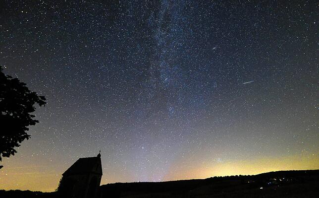 Eine Sternschnuppe der Perseiden ist bei Mörsingen auf der Schwäbischen Alb neben der Milchstraße am Himmel zu sehen.
