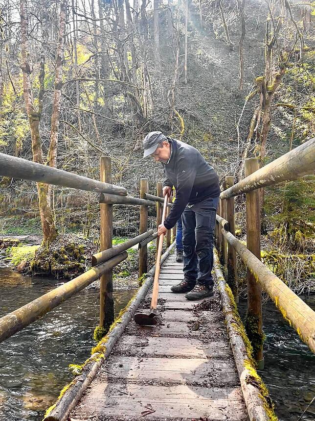 Vereinsmitglied Ludwig Rieger befreit einen der Stege in der Gauchachschlucht vom rutschigen Moos (Archivbild).