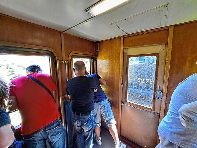 Viele Bahnfans schauen im vordersten Wagen begeistert auf die Lok.