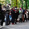 Menschen mit Mund- und Nasenschutz stehen in einer langen Schlange vor einer Arztpraxis im Berliner Bezirk Neukölln für einen ...