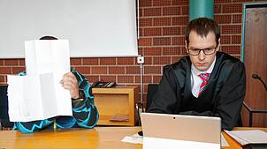 Am Tag des Urteils vor dem Landgericht Konstanz verbirgt André Rehm sein Gesicht hinter Akten. Neben ihm sitzt sein Anwalt Michael Busching.