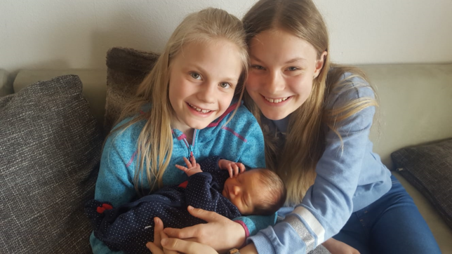 Lilith (9 Jahre) und Fiona (12 Jahre) freuen sich darüber, ihre kleine Schwester Salome endlich im Arm halten zu dürfen.