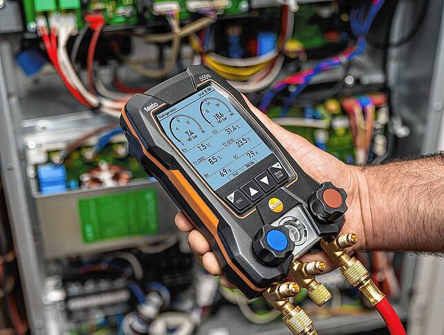 Ein Monteur prüft mit Testo-Technik eine Klimaanlage.