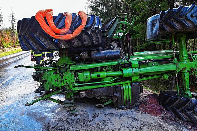 Der Traktor liegt auf der Seite. Das linke Hinterrad fehlt.