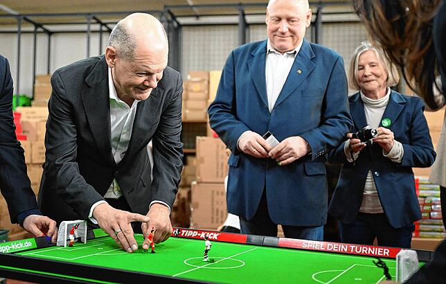 Bundeskanzler Olaf Scholz beim Spielen, Geschäftsführer Mathias Mieg schaut zu.