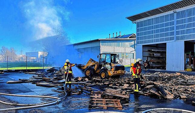 Die Feuerwehr löschte das brennende Dämmmaterial mit mehreren Rohren unter Atemschutz ab. Mithilfe eines Radladers mussten die Stapel ...